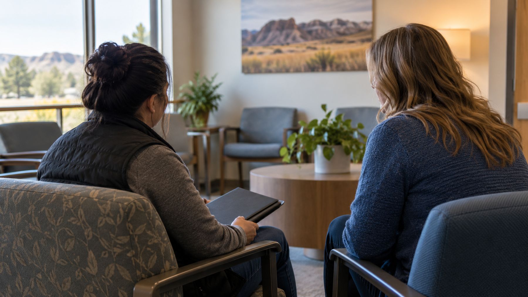 Two women sitting and talking quietly in a waiting area